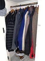 Full view of multiple men's jackets and coats hanging on a rod including nylon, wool, and other materials in various colors.