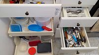 Overall view of two open kitchen drawers and a cabinet shelf showing plastic food storage containers with lids, and assorted utensils and flatware.