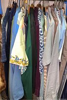Photo of casual men's shirts on hangers, showcasing various colors and patterns including navy, green, purple, and checked designs.