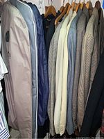 Photo showing a row of various men's jackets on wooden hangers, including beige, blue, gray, and patterned sport coats.