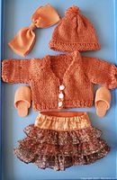 Full set showing sweater, hat, skirt, bow and slippers arranged in display box