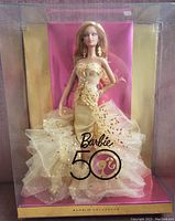 Full view of Barbie doll in box showing gold chiffon and sequin layered dress with 50th anniversary logo