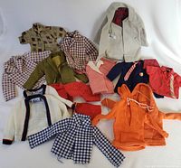 Full collection of vintage Ken doll casual clothes including shirts, jackets, shorts in various styles and colors laid out on white backdrop