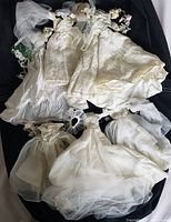 Overview of six vintage Barbie wedding gowns with trains and accessories, laid on a dark fabric background