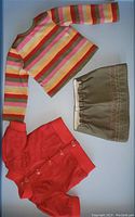 Three piece set of 18 inch doll clothes: striped long sleeve top, khaki skirt, red snap closure jacket.