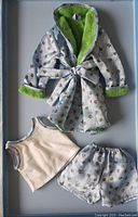 Light blue floral pajama shorts, cream sleeveless top with grey trim, and light blue floral robe with bright green lining laid flat in a box