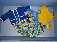 Full set of doll clothes and accessories displayed flat including jacket, shirt, skirt, shoes, clutch purse, and hanger