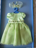 Photo of entire dress on hanger with matching headband above on blue tray background