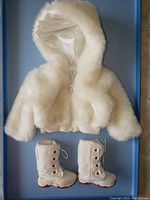 Full outfit laid flat showing white fur hooded winter coat and pair of white boots with red soles, front view