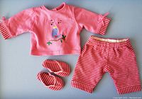 Front view of the pink shirt with bird print, striped shorts, and matching striped sandals arranged on a flat surface