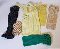 Overview of six vintage Barbie clothes laid flat on a white surface showing colors and styles