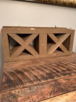 Stack of 8 brown stained wooden fence toppers with crossed X frame design, showing the front view of the toppers.