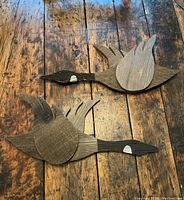Front view of pair of barnboard wooden Canadian geese wall hangings on rustic wooden floor.