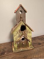 Front and side view of rustic wooden birdhouse showing two circular entry holes and a tall chimney structure at the back