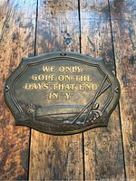 Front view of the golf plaque showing the raised gold text and golf club relief on a rustic wooden surface.