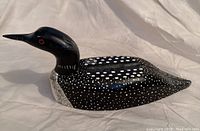 Side angle view of carved wooden loon decoy showing painted details and shape.
