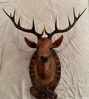 Front view of vintage plastic deer wall decor with detailed antlers and wooden plaque mount