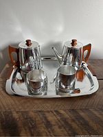 Front view of the full tea and coffee set including tray, both pots with lids and wood handles, creamer, and sugar bowl.