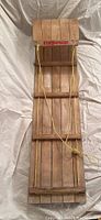 Full top view of the wooden toboggan showing the length and curved front with pull rope.
