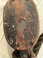 Front and side view of the wooden block and tackle pulley with attached rope, showing incised maker's mark and wear.