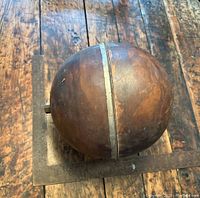 Copper float ball shown from side, highlighting seam and dent