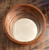 Top-down view showing round mirror surface and wood frame interior with factory hash marks or numbering.