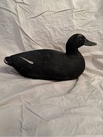 Left side view of vintage painted wooden duck decoy showing black paint with some worn areas.