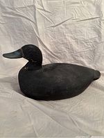 Front side view of vintage painted wood duck decoy, showing black paint, carved feather texture, and turned neck.