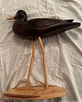 Side view of the full wooden Willet Sandpiper carving on its base, showing the body and long legs.