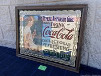 Full view of the Coca Cola vintage advertising mirror showing frame, entire mirrored surface, and painted advertisement with a woman holding a glass of Coca Cola.