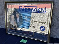 Front view of the mirror showing the full printed advertisement with text and graphic illustration of a man and woman.