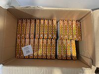 Top-down view of a box containing 27 copies of Baby Touch and Feel Farm Animals books stacked upright showing the spine design.
