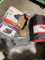 Photo of Outbound single air beds 2-pack box, Bestway 12V air pump box, and black Outbound sleeping bag in stuff sack on floor.