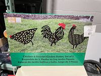 Box front showing art of three metal chicken/rooster garden stakes and product name.