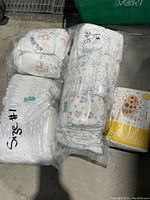Lot of four packages of new infant disposable diapers, two labeled Size 1 and two unlabeled but smaller, presumed Newborn size.