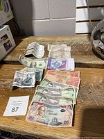 Overview of various foreign currency including Jamaican and Indian notes on a wooden surface