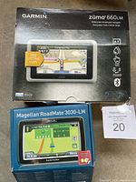 Original packaging boxes for Garmin Zumo 660LM and Magellan RoadMate 3030LM GPS units, showing front and branding details