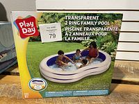 Box showing Play Day branded transparent 2 ring family inflatable pool with children playing inside on packaging, dimensions 103" x 62.5" x 18" (262 cm x 159 cm x 46 cm).