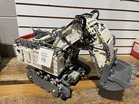 Front side of assembled excavator showing bucket, tracks, main body
