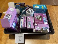 Photo showing multiple boxed Philips light bulbs, both 50W and 60W wattages in a black plastic container.