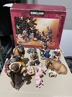 Photo shows the Kirkland Signature box and 14 nativity figurines displayed on a table including humans and animals with donkey ear visible as broken.