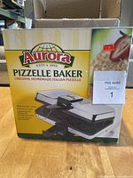 Front view of the Aurora Pizzelle Baker original cardboard box with branding and product details.