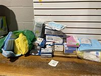 Full overview photo showing PPE items stacked on a table including gloves, gowns, masks, and wipes in original packaging