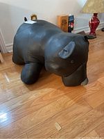 Side view of the black leather bear ottoman showing the shape and panel stitching.