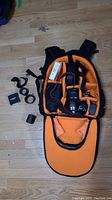 Backpack open, interior filled with camera body, lens, flash, charger and accessories
