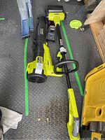 Overhead view showing leaf blower, patio cleaner head, battery and charger laid out on metal floor.