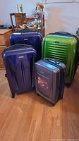 Four suitcases grouped on hardwood floor showing overall lot composition