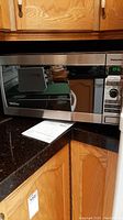 Full view of Panasonic microwave on kitchen counter showing stainless steel and black design with control panel and handle.