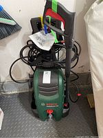 Bosch pressure washer unit with coiled hose and attached manual, positioned on floor.