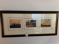 Framed triptych of three Tom Thomson prints, with a wide dark frame and gold inner trim, overall measurements about 44x20 inches.